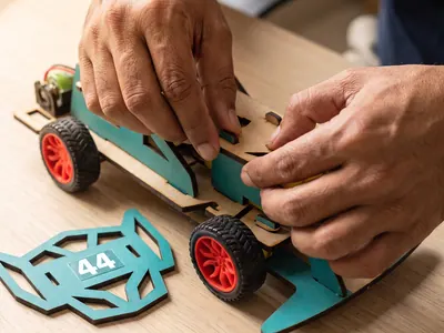 Adult hands pressing a teal laser-cut part into place by hand